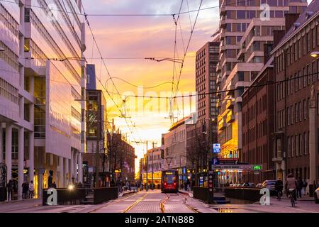 Den Haag, Niederlande - 15. Januar 2020: Belebte Straße mit Straßenbahn- und Bürogebäuden während des Sonnenunterens in den Haag, Niederlande Stockfoto