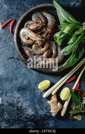 Rohe Garnelen Garnelen mit asiatischen Nudeln, Koknussmilch und Gemüse. Zutaten für asiatische Küche oder thailändische Suppe tom Yum. Dunkler Betonhintergrund. Stockfoto