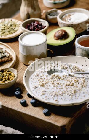 Gesundes Frühstück. Verschiedene Frühstücksküche mit gerountem Weizen, Joghurt, Kefir, Hüttenkäse, Avocado, Roggenbrot, Samen, Nüssen und Beeren Sortiment i Stockfoto