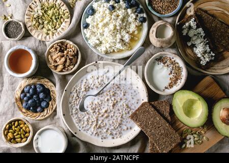 Gesundes Frühstück. Verschiedene Frühstücksküche mit gerountem Weizen, Joghurt, Kefir, Hüttenkäse, Avocado, Roggenbrot, Samen, Nüssen und Beeren Sortiment i Stockfoto