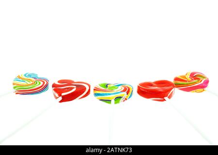 Foto schöner Regenbogen herzförmige Lollipop-Süßigkeiten auf weißem Hintergrund, Valentinstag Konzept Stockfoto