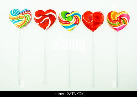 Foto schöner Regenbogen herzförmige Lollipop-Süßigkeiten auf weißem Hintergrund, Valentinstag Konzept Stockfoto