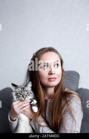 Nahaufnahme der jungen selbstbewussten, attraktiven Frau mit ihrer niedlichen Katze, Frau mit langen Haaren, die wegschaut Stockfoto