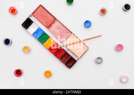 Palette mit Farben und Pinsel auf weißem Hintergrund. Farbige kleine Farbengefäße. Satz Künstler für Make-up und Zeichnung. Schulung in Zeichnen und Kunst Stockfoto