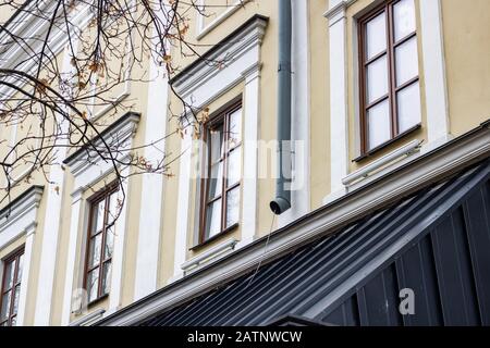 Fenster im Retro-Stil und Drainpipe an einer gelben Wand Stockfoto