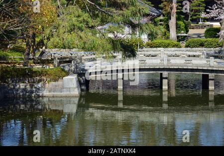 Am Wasser des Teiches verbindet eine kleine Steinbrücke die beiden Ufer Stockfoto