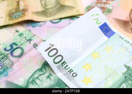 Eine 100-Euro-Banknote, die über einem Stapel chinesischer Yuan-Banknoten angeordnet wurde. Stockfoto