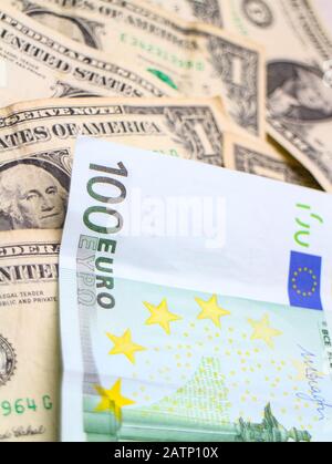 Eine 100-Euro-Banknote, die über einen Stapel US-Dollar-Banknoten angeordnet wurde. Stockfoto
