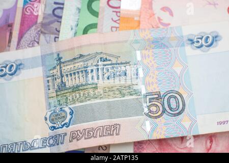 Eine russische Rubel-Banknote, die über einem Regenbogen von Banknoten verschiedener Weltwährungen angeordnet wurde, darunter Euro-Banknoten, australische Dollar und Schekel. Stockfoto