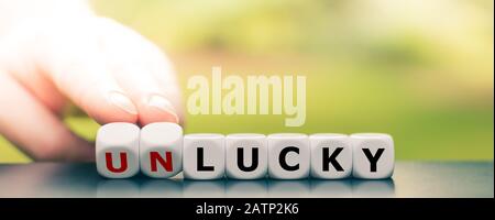 Hand dreht Würfel und ändert das Wort "Pech" in "Lucky". Stockfoto