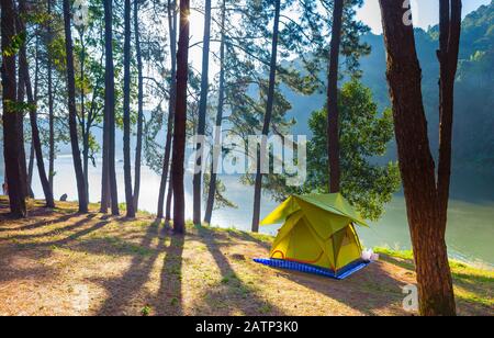 Abenteuer Camping Tourismus und Zelt unter der Aussicht Kiefernwaldlandschaft in der Nähe von Wasser im Freien am Morgen und Sonnenuntergang Himmel am Pang Oung, Royal Forest Park, Stockfoto