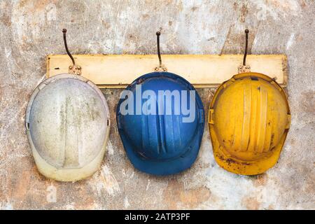 Drei Bauhelme, die an einem alten Holz-Hutträger hängen Stockfoto