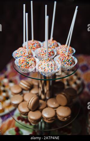 Schokoladenmakronen liegen auf einer Glasslide für Desserts. Bartisch mit Süßigkeiten. Kuchen und andere Süßigkeiten. Stockfoto