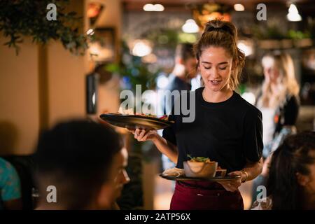 Eine Kellnerin, die Kunden in einem Restaurant in Newcastle-Upon-Tyne Essen serviert. Stockfoto