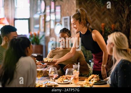 Eine Kellnerin, die Kunden in einem Restaurant in Newcastle-Upon-Tyne eine Mahlzeit serviert. Stockfoto