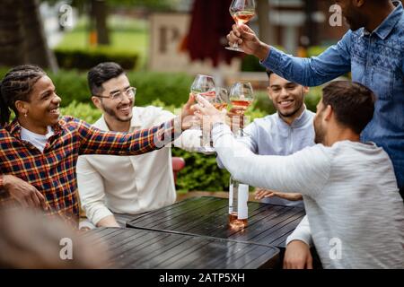 Eine Gruppe von männlichen Freunden, die zusammen Wein und einen festlichen Toast haben. Stockfoto