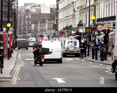 Queensway, London, Großbritannien. An einem Freitagnachmittag ist es voll mit Autos, Fahrrädern und Menschen Stockfoto