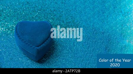 Herzförmige Ringbox aus blauem samt mit Glitzern auf trendig blauem Hintergrund. Geschenk für Valentinstag oder Geburtstag. Platz für Text kopieren Stockfoto