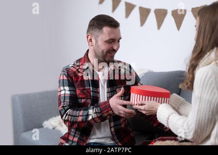 3/4-Ansicht des Mädchens, das valentinsgeschenk dem Freund präsentiert. Stockfoto