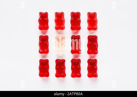 Weißer Gummibär unter roten Gummibären. Unterscheidung und Vielfalt Stockfoto