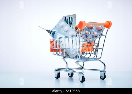 Medizinische Pillen in Blisterpackungen und eine Spritze in einem Warenkorb auf weißem Hintergrund mit Kopierraum Stockfoto