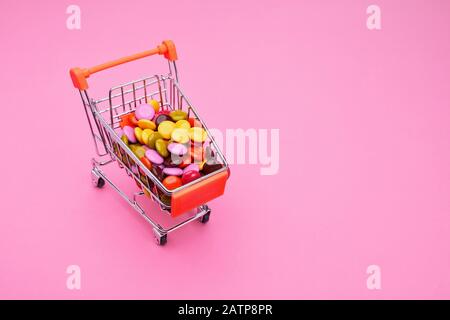 Einkaufswagen voller bunter, zuckerbeschichteter Schokoladepillen Stockfoto