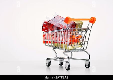 Einkaufswagen mit farbenfrohen Geschenkschachteln auf weißem Hintergrund. Kaufkonzept für weihnachten oder den schwarzen freitag. Stockfoto