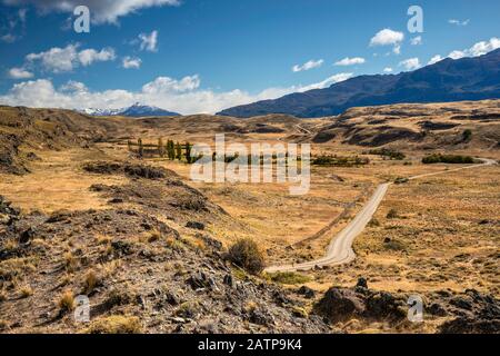 Straße, vulkanische Felsen im Grasland des Chacabuco Valley, zukünftiger Patagonia-Nationalpark, in der Nähe von Cochrane, Chile Stockfoto