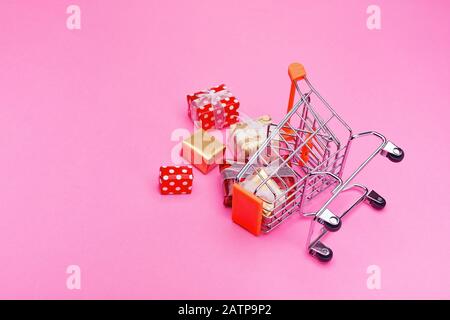Umgestürzter Warenkorb mit Geschenkschachteln, die über den ganzen Boden auf pinkfarbenem Hintergrund verschüttet wurden Stockfoto