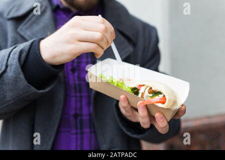 Der Mann hält Falafel-Sandwich in Papiertüte. Gesundes Straßennahrungskonzept, orientalische Küche Stockfoto