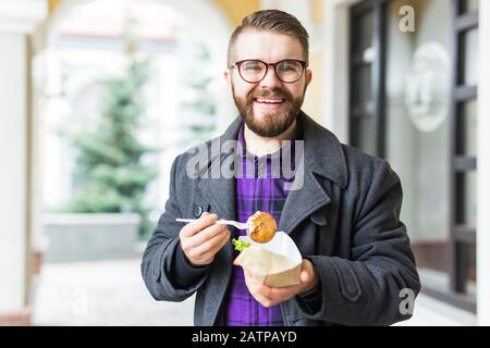 Mann mit einem Teller mit traditioneller jüdischer Speisefalafel aus Kichererbsen beim Straßennahrungsfest. Stockfoto