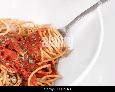 Spaghetti-Makro für Ganzweizen. Gabel in weißer Schüssel. Marinara-Sauce mit Cilantro und Pfeffer. Stockfoto