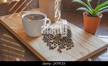 Frisch gebrühter Kaffee mit Kaffeebohnen und Holzschneidebrett. Küche Innenbereich. Stockfoto