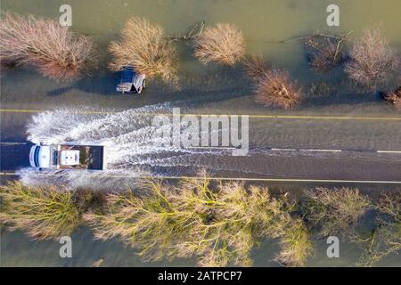 Das Bild vom 27. Januar zeigt ein Fahrzeug, das an Autos vorbeifährt, die bei den letzten Überschwemmungen auf der A1101 an der Grenze zu Cambridgeshire/Norfolk gefangen wurden und jetzt gerade sichtbar sind, nachdem das Hochwasser untergegangen ist. Das Hochwasser entlang eines berüchtigten Straßenabschnitts in Welney an der Grenze zu Cambridgeshire/Norfolk hat nachgelassen und enthüllt heute unglaubliche VIER gestrandete Autos (Mon). Die Autofahrer waren alle von dem seit zwei Monaten überschwemmten langen und kurvenreichen Straßenabschnitt erfasst. Vier Personen mussten von den Feuerwehrleuten aus einem der Autos gerettet werden, nachdem sie am Welney Wash auf Janu gefangen wurden Stockfoto