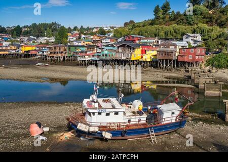 Fischerboot bei Ebbe, Palafitos, Holzstelzenhäuser in Castro, Isla Grande de Chiloe, Region Los Lagos, Patagonien, Chile Stockfoto