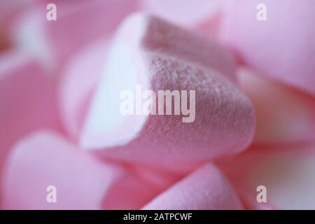 Ein Haufen Marshmallows in Form von Herzen auf einem rosafarbenen Hintergrund. Das Konzept des Valentinstages, der Liebe, der Süßigkeiten Stockfoto