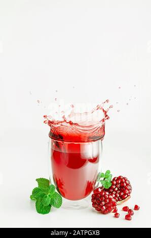 Granatapfelsamen fliegen über spritzenden Saft in einem Glas. Gesundes Lifestyle-Konzept. Stockfoto