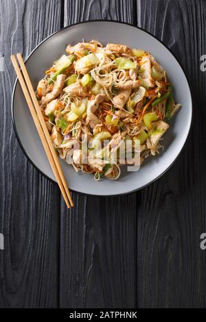 Köstliche philippinische Speisen Pancit Bihon Reisnudeln mit Gemüse und Fleisch in einem Teller auf dem Tisch. Vertikale Draufsicht von oben Stockfoto