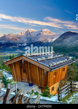 Traditionelle Holzhütte, dahinter das massiv des hohen Goell im Winter, Nationalpark Berchtesgaden, Schönau am Koenigssee, Berchtesgadener Land Stockfoto