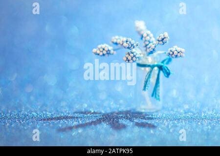 Nahaufnahme künstlicher Blumen in einer Glasvase auf blauem unscharfen Hintergrund für den Valentinstag Stockfoto