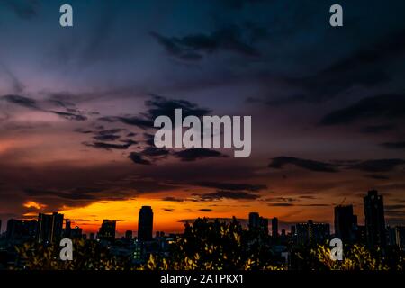 Natürlichen Sonnenuntergang am Abend in der Innenstadt Silhouette in Bangkok. Helle Dramatischer Himmel und dunklen Boden. Stadt Landschaft unter malerischen bunten Himmel bei Sonnenuntergang. Su Stockfoto