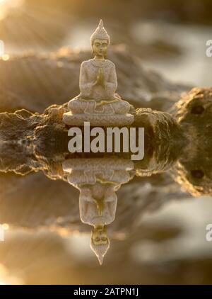 Ein buddha auf den Felsen und seine Reflexion im Wasser, Manipulation Stockfoto