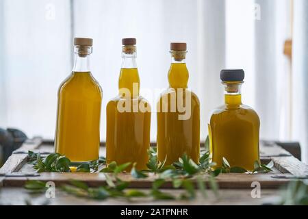 Vier Glasflaschen mit frischem biologischem Olivenöl oder Speiseöl in einer alten Küche in Griechenland Stockfoto