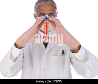 Labortechniker, der eine Durchstechflasche mit roter Flüssigkeit in beiden Händen vor seinem Gesicht hält. Der Mann trägt einen Labormantel und eine Schutzmaske, um ein Anstecken zu verhindern Stockfoto