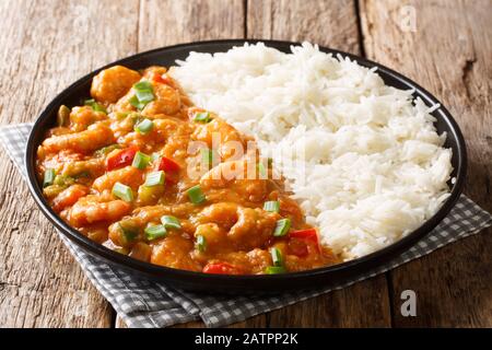 Servieren von Garnelen Etouffee mit Gemüse und Sauce, serviert mit Reisverschluss in einem Teller auf dem Tisch. Horizontal Stockfoto