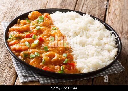 Würziger traditioneller Garnelenetouffee mit Sellerie, Zwiebel und Pfeffer mit Soße, serviert mit Reisverschluss in einem Teller auf dem Tisch. Horizontal Stockfoto