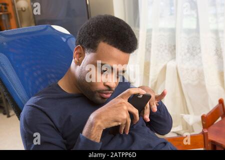 Junger Mann mit Behinderung, der ein Smartphone hält Stockfoto