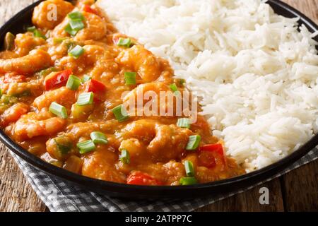 Louisiana Shrimp Etouffee mit Gemüse, das in roux Soße gekocht wird, serviert mit Reisverschluss in einem Teller auf dem Tisch. Horizontal Stockfoto