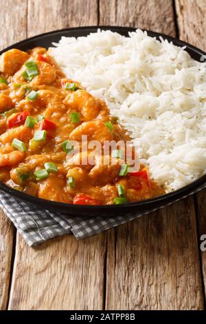 Garnele Etouffee Saftiges Gericht, das in reicher und aromatischer Roux-Sauce verraucht ist und mit Reisverschluss in einem Teller auf dem Tisch serviert wird. Vertikal Stockfoto