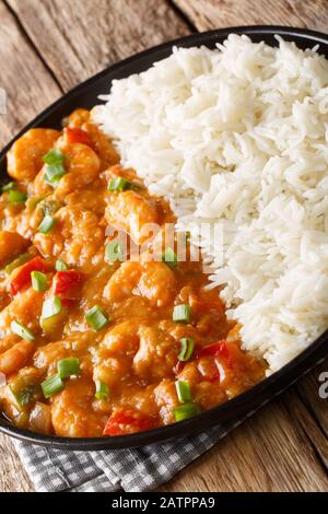 Garnele Etouffee klassischer Louisiana Eintopf besteht aus Garnelen, Zwiebeln, Sellerie und grünem Pfeffer, der mit Reisverschluss in einem Teller auf dem Tisch serviert wird. Vertikal Stockfoto